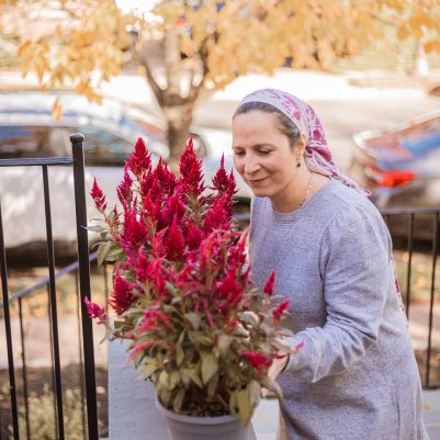 Woman smelling flowers on porch 1