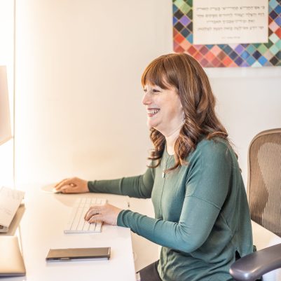 Smiling woman sitting at desk looking at computer 1
