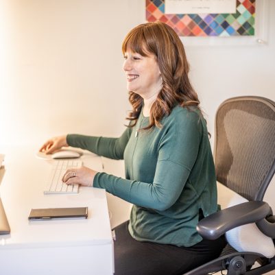 Smiling woman sitting at desk looking at computer 2