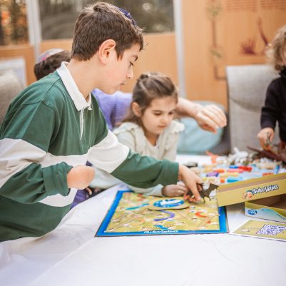 Siblings playing board game in Sukkah