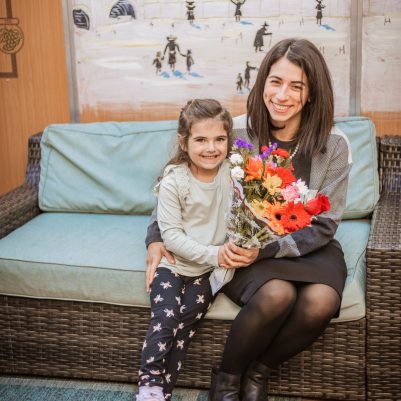 Smiling mother and daughter holding flowers