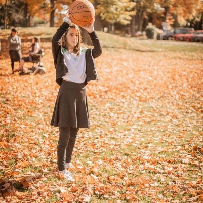 Girl throwing basketball in park
