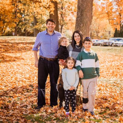Family smiling at park with leaves on ground 4