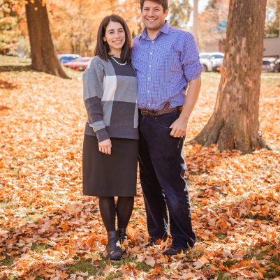 Couple smiling at park with leaves on ground 1
