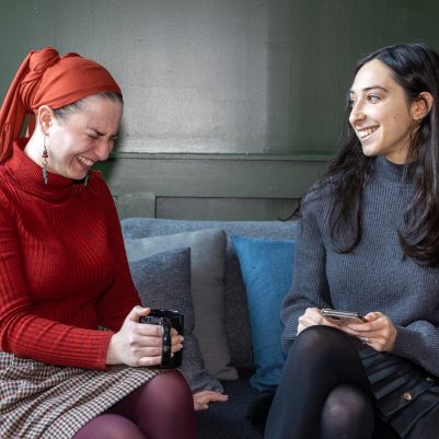 Two women sitting on couch laughing