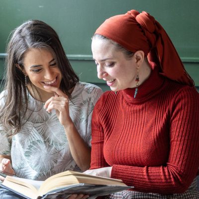 Two women looking at book on couch