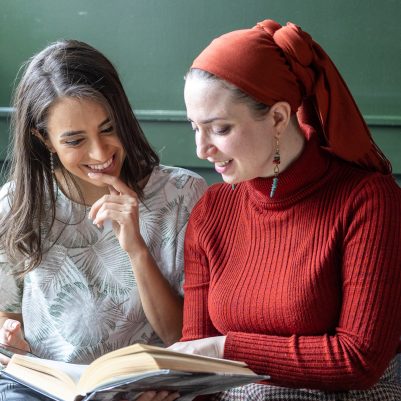 Two women looking at book on couch