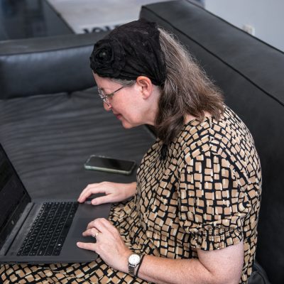 Woman sitting on couch working on laptop 1