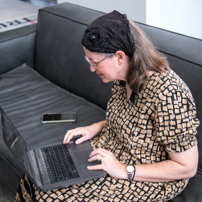 Woman sitting on couch working on laptop 2