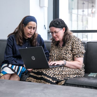 Two women sitting on couch looking at laptop 2