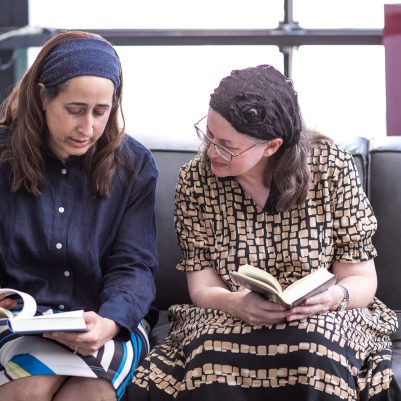 Two women studying book on couch 3