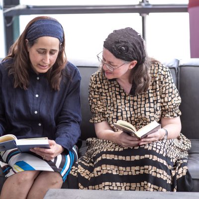 Two women studying book on couch 4