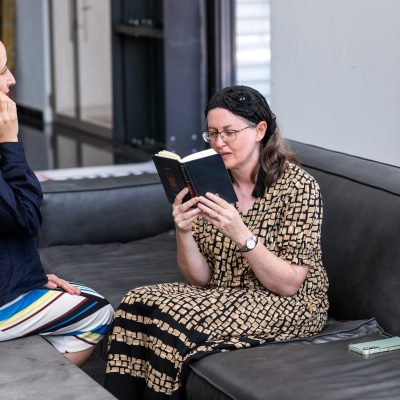 Woman praying next to friend looking at phone 1