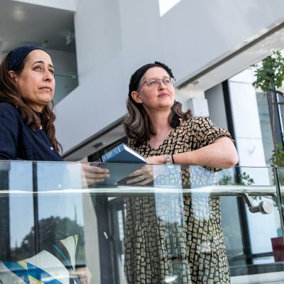 Two women talking and holding siddurs 2