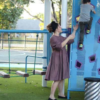 Mother Helping Young Boy on Colorful Playground Climbing Wall