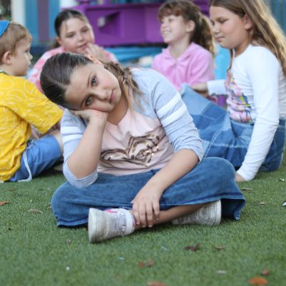 Sad Girl Resting Head on Hand Sitting Alone on Grass at Playground