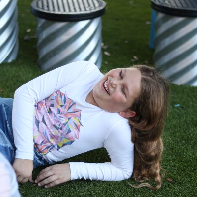 Young Girl Laughing While Lying on Grass at an Outdoor Playground