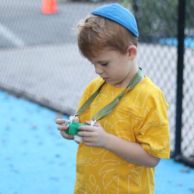 Young Boy Holding a Toy Near an Outdoor Play Area