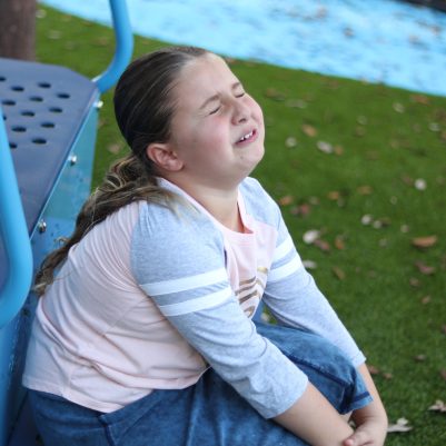 Young Girl Crying and Experiencing Knee Pain While Resting at a Playground