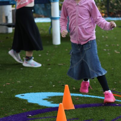 Young Girl Jumping Over Cones in a Playground