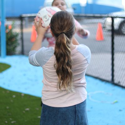 Two Young Girls Playing Catch with a Ball at an Outdoor Playground