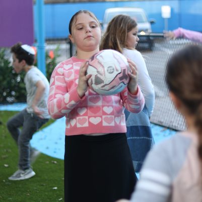 Young Girl Holding a Ball While Playing Catch with Friends at a Playground