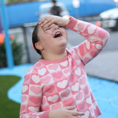Child Experiencing Head Pain While Standing at an Outdoor Playground