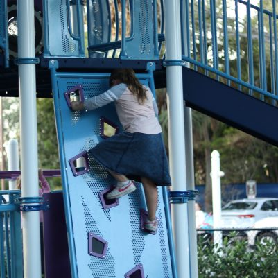 Young Girl Climbing a Playground Wall