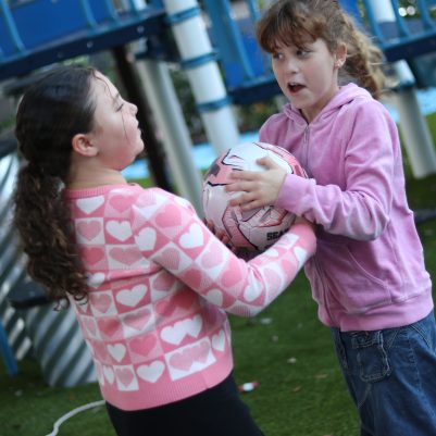Two Girls Playing with a Ball in Playground Setting