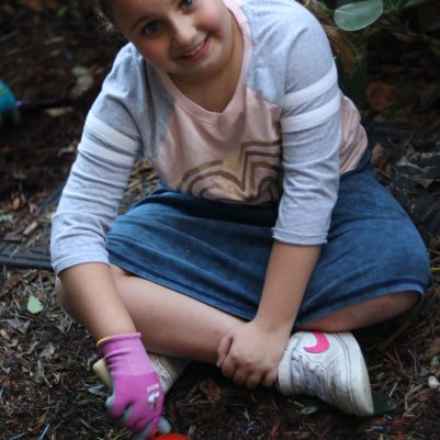 Smiling Young Girl Gardening and Digging in Soil