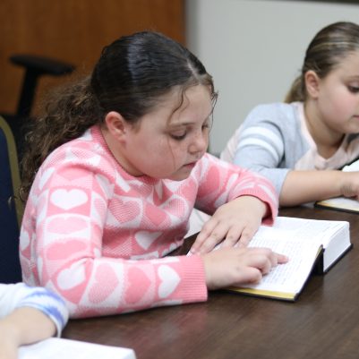 Three Young Girls Learning and Reading Books Together in a Quiet Study Room