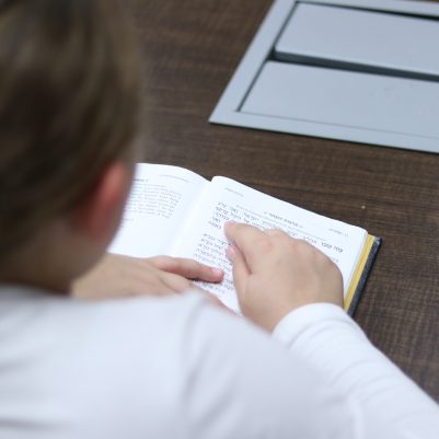 Child Focused on Reading While Studying at a Table
