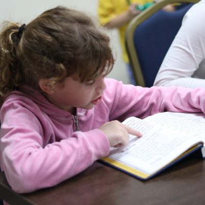 Young Girl Concentrating on Reading an Open Book During Study Time