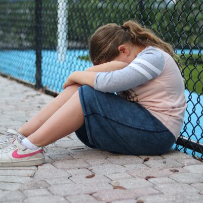 Sad Young Girl Sitting Alone and Crying at an Outdoor Playground