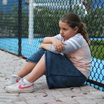 Sad Young Girl Sitting Alone at an Outdoor Playground