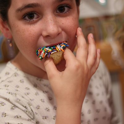 Young Girl Eating a Sprinkle Cupcake at an Indoor Birthday Party