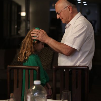 Elderly Man Praying for Young Girl During Candle Lighting Ceremony