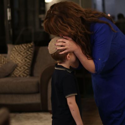 Woman Praying for a Young Boy and Kissing His Forehead
