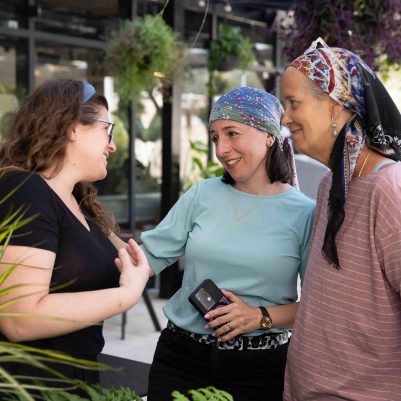 Three Women Laughing and Talking in an Outdoor Garden