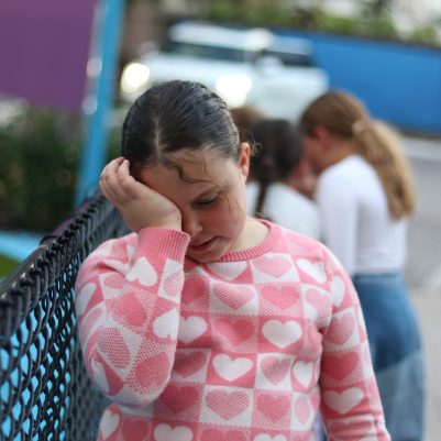 Young Girl Crying and Standing Alone While Other Kids Play Nearby