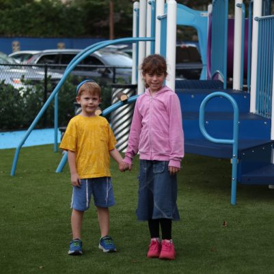 Young Boy and Girl Standing Together and Holding Hands at a Playground