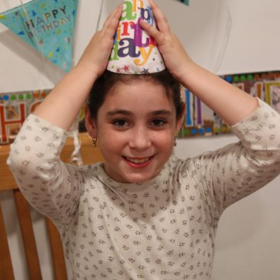 Smiling Young Girl Wearing a Birthday Hat