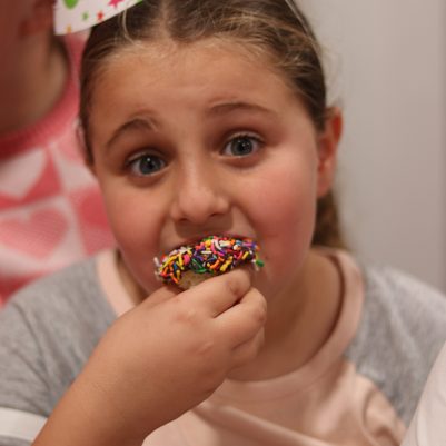 Young Girl Wearing a Birthday Hat Enjoying a Sprinkle Cupcake