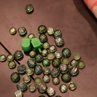 Traditional Dreidel Game with Green Marbles on a Table