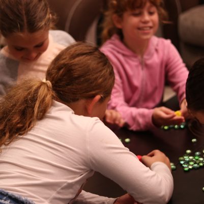 Group of Young Girls Enjoying a Traditional Dreidel Game Indoors