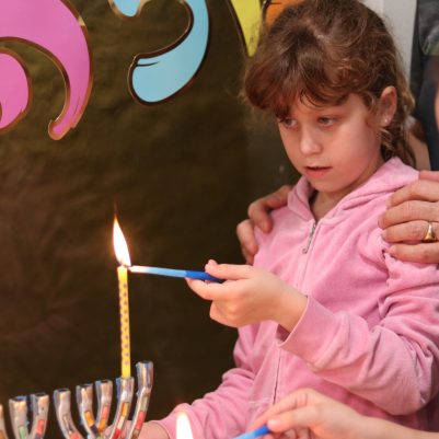 Young Girl Lighting Candles with Grandparents at Home