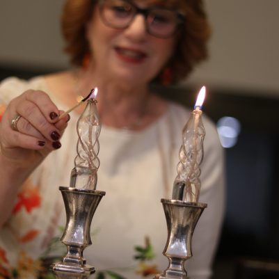 Elderly Woman Smiling and Lighting Candle