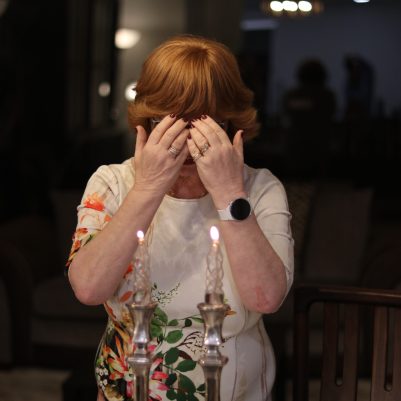 Elderly Woman in Prayer During Candle Lighting Ceremony