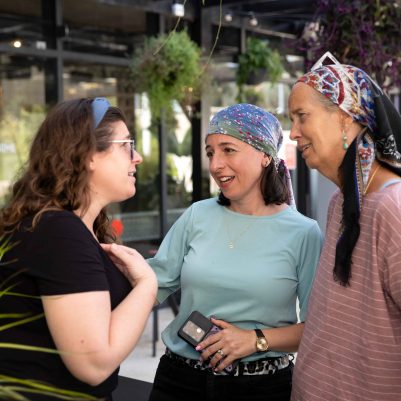 Three Women Smiling and Talking in an Outdoor Space