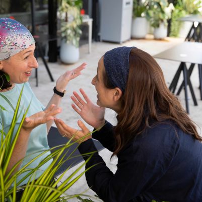Two Women Laughing and Talking in an Outdoor Coffee Shop